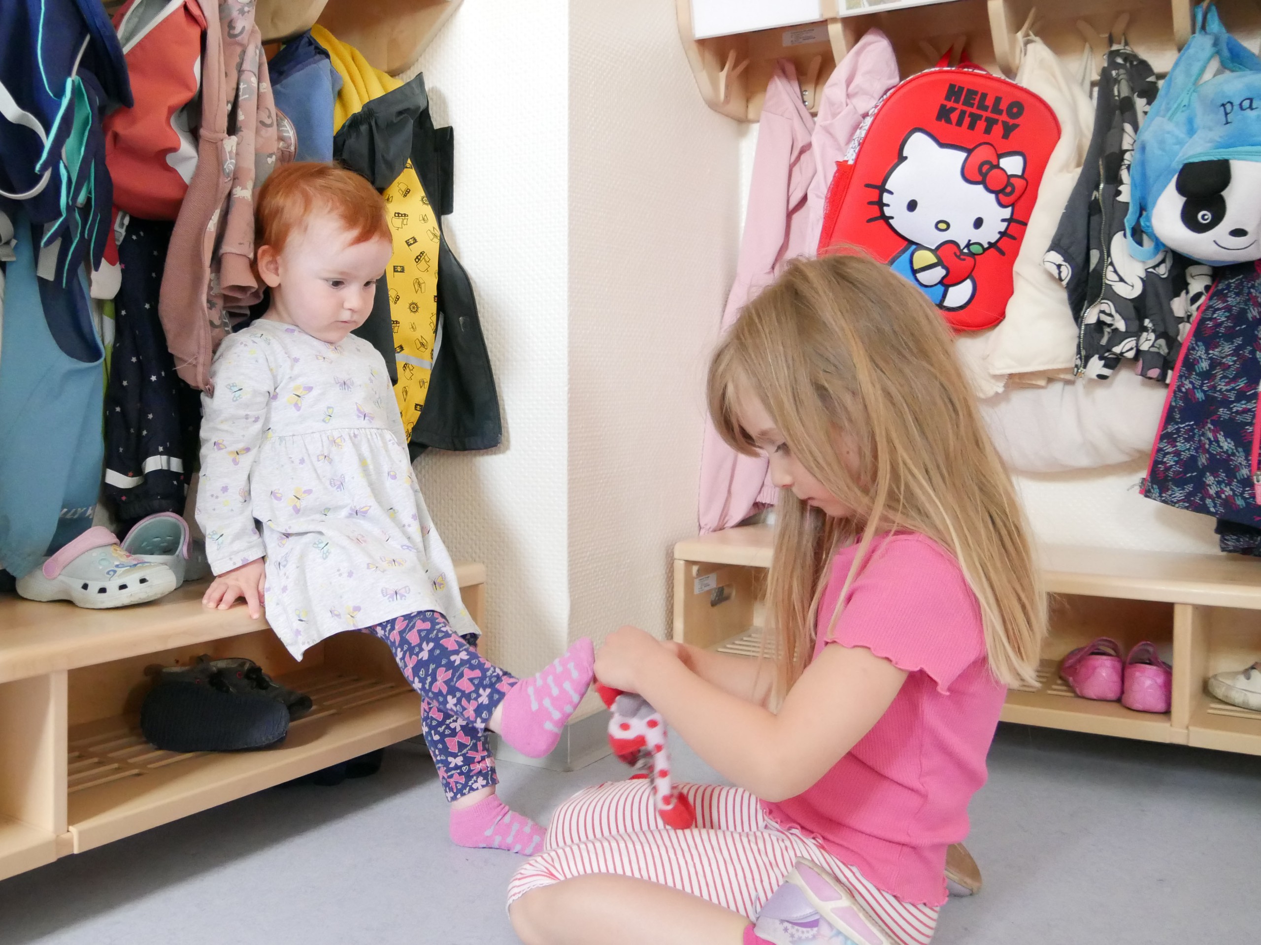 Ein Kind hilft einem anderen dabei, Socken anzuziehen