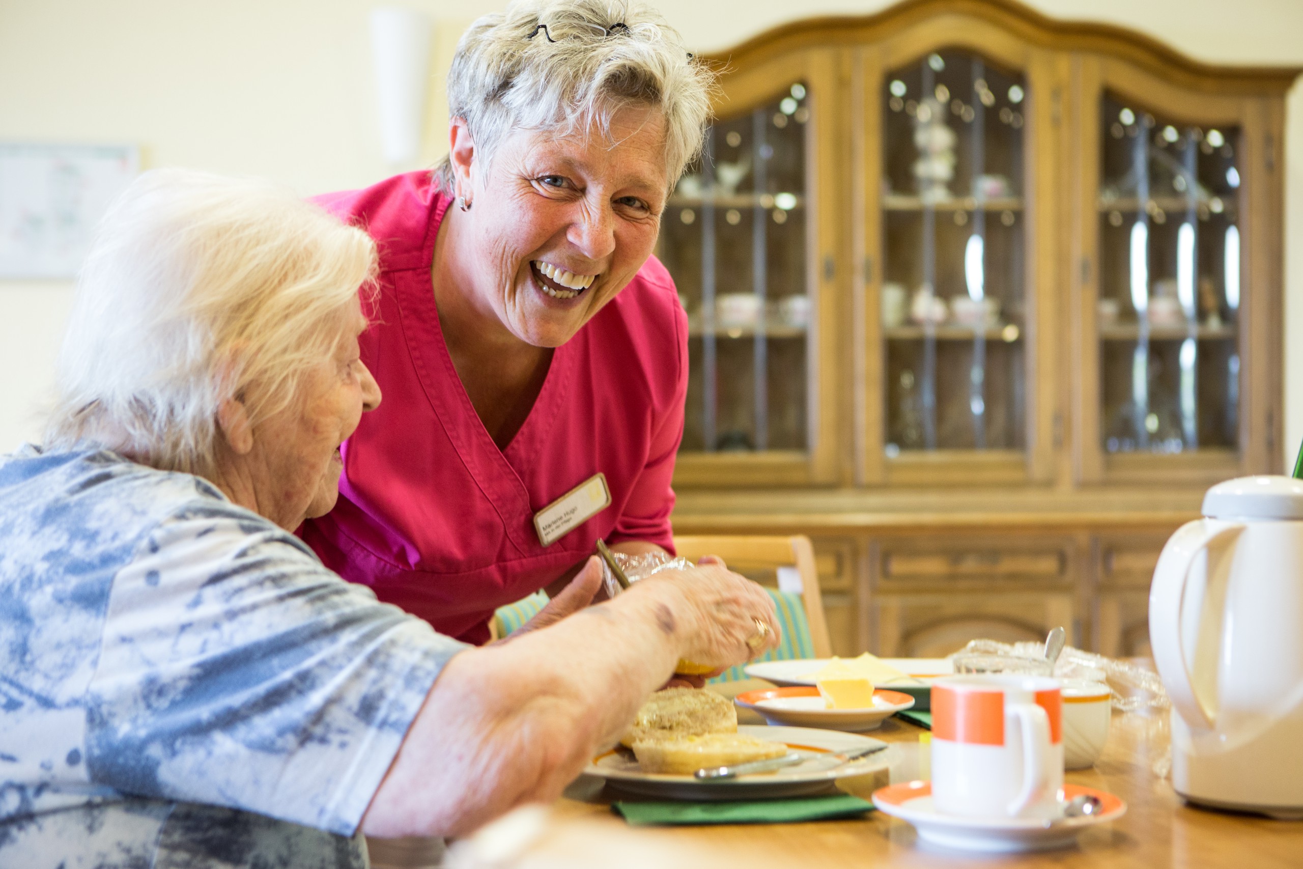 Zwei lachende Personen an einem Esstisch